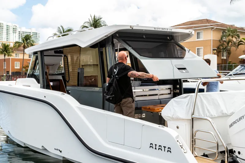 Slide: The Image of Aiata Wayfinder 38 Cabin 2026, modern boat docked with people. - 2