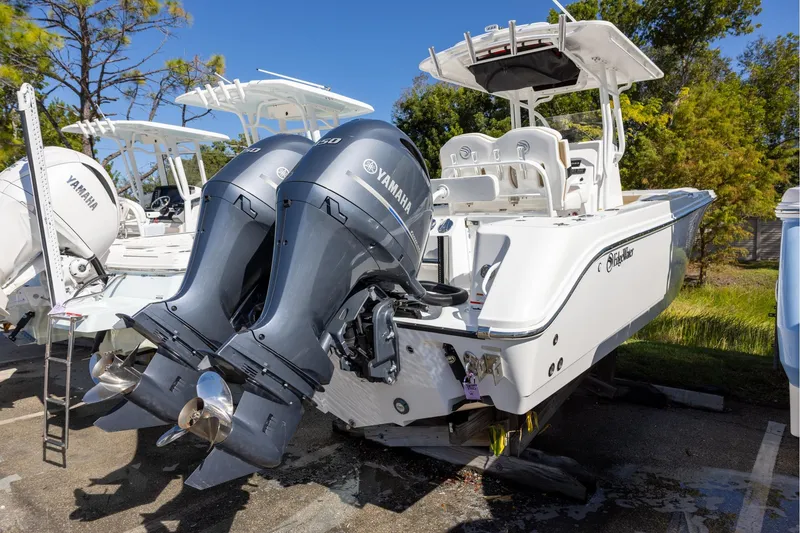 Slide: The Image of 2023 Edgewater 245CC boat with dual Yamaha outboard engines, parked outdoors. - 2