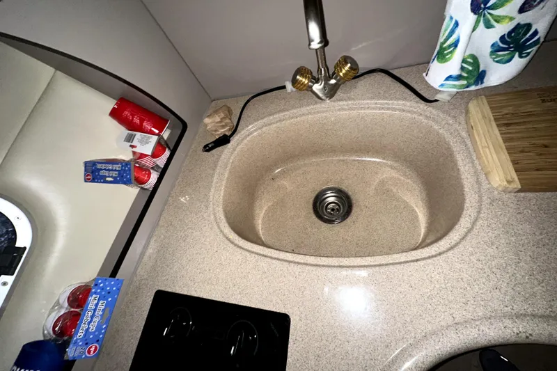 Slide: The Image of Compact kitchen sink area in a 2002 Four Winns 378 Vista boat, featuring a faucet and countertop. - 35