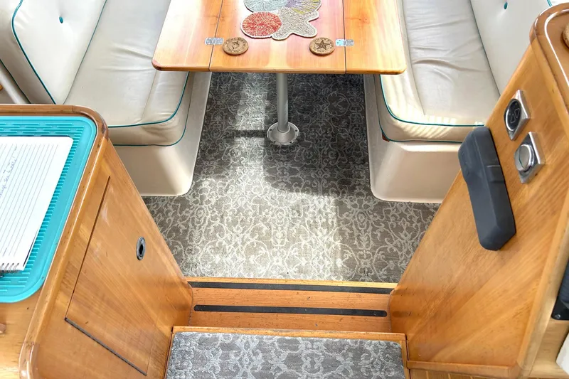 Slide: The Image of 2004 PDQ 34 Power Catamaran interior with wooden table, cushioned seating, and patterned carpet. - 28