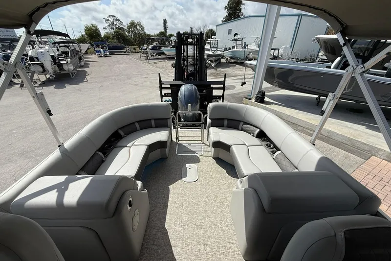 Slide: The Image of 2022 Bennington 25 LFB pontoon boat with spacious seating and modern design at a marina. - 22