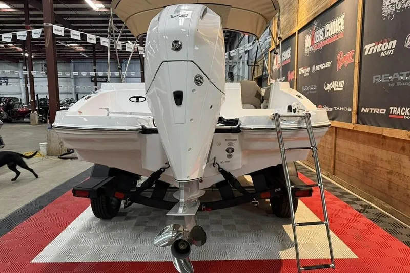 Slide: The Image of 2026 Tahoe 2150 boat displayed indoors with outboard motor and ladder. - 6