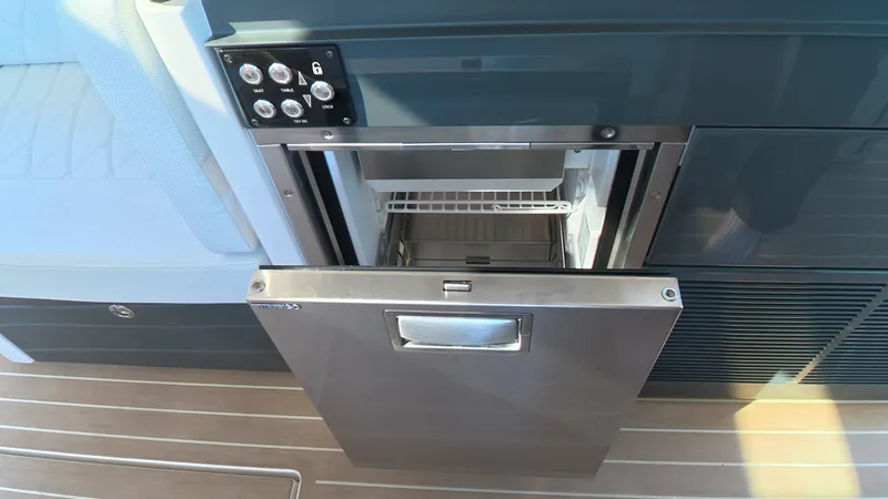 Slide: The Image of An open refrigerator on a boat with wooden flooring and blue walls. - 20