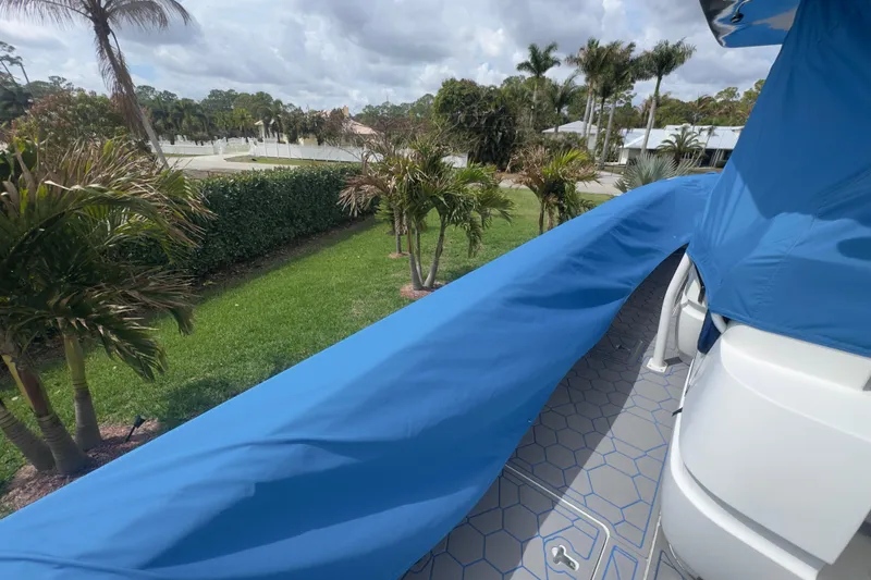 Slide: The Image of 2007 Intrepid 370 Center Console boat with blue cover, surrounded by lush greenery. - 102