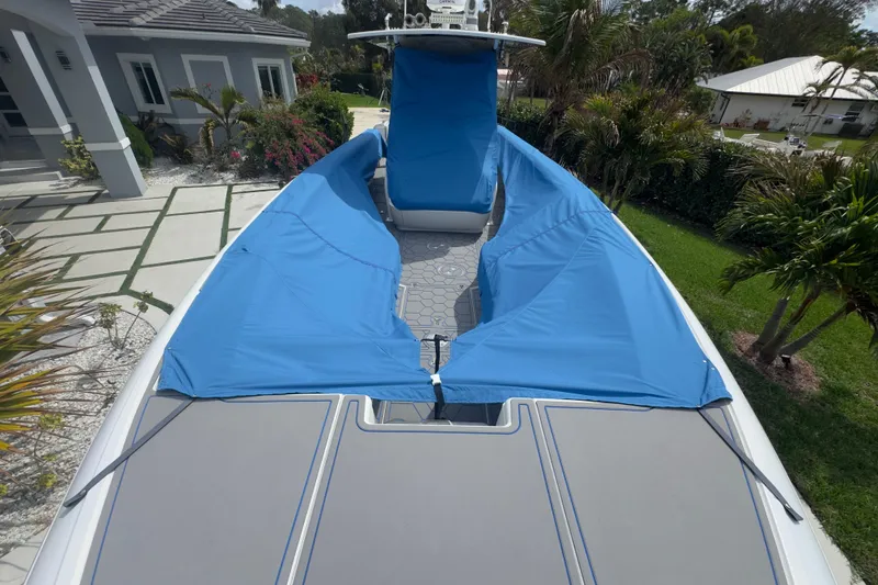Slide: The Image of 2007 Intrepid 370 Center Console boat with blue covers, parked near a modern house. - 3