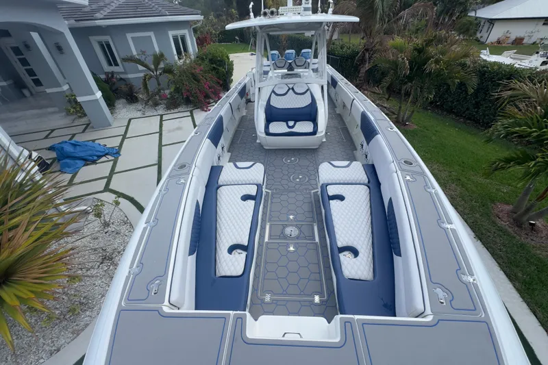 Slide: The Image of 2007 Intrepid 370 Center Console boat with blue and white seating, docked near a modern house. - 4