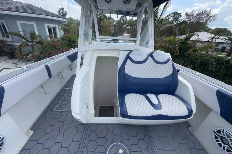 Slide: The Image of 2007 Intrepid 370 Center Console boat with blue and white seating, docked near a garden. - 78