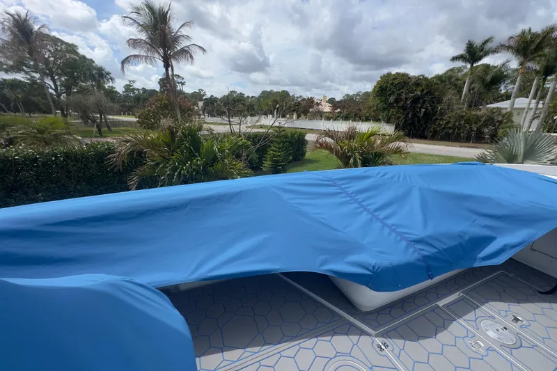 Slide: The Image of Covered 2007 Intrepid 370 Center Console boat with blue tarp, surrounded by tropical greenery. - 98