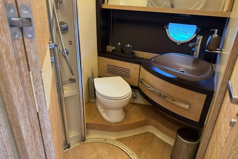 Slide: The Image of Luxurious bathroom interior of a 2014 Azimut 64 yacht, featuring modern fixtures and porthole window. - 30