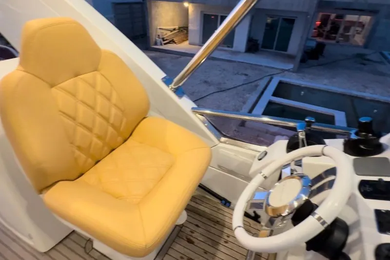 Slide: The Image of Front view of a 2014 Azimut 64 yacht docked in a scenic canal setting. - 7