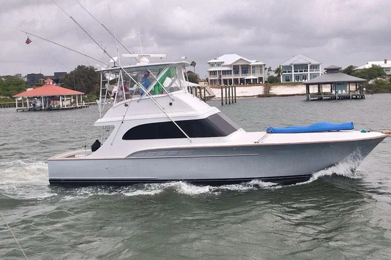 Slide: The Image of 1988 Buddy Davis 47 Convertible yacht cruising near waterfront homes. - 2