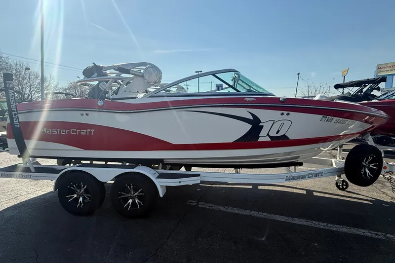 Slide: The Image of 2013 MasterCraft X10 boat on trailer, red and white design, parked outdoors. - 3