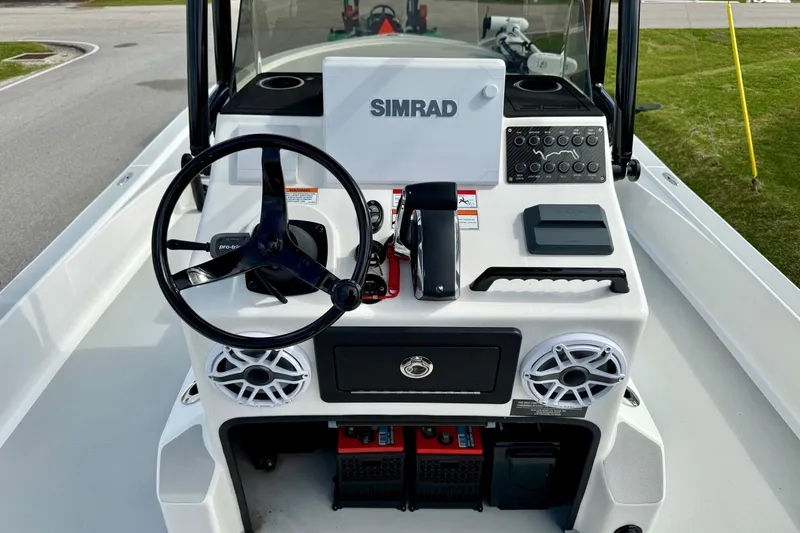 Slide: The Image of 2025 Shallow Sport boat dashboard with steering wheel, Simrad display, and control panel. - 10
