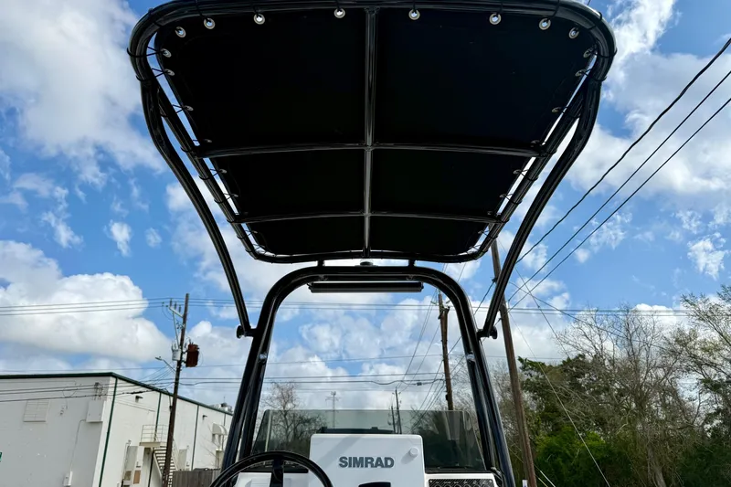 Slide: The Image of 2025 Shallow Sport boat with T-top and Simrad electronics under a blue sky. - 11