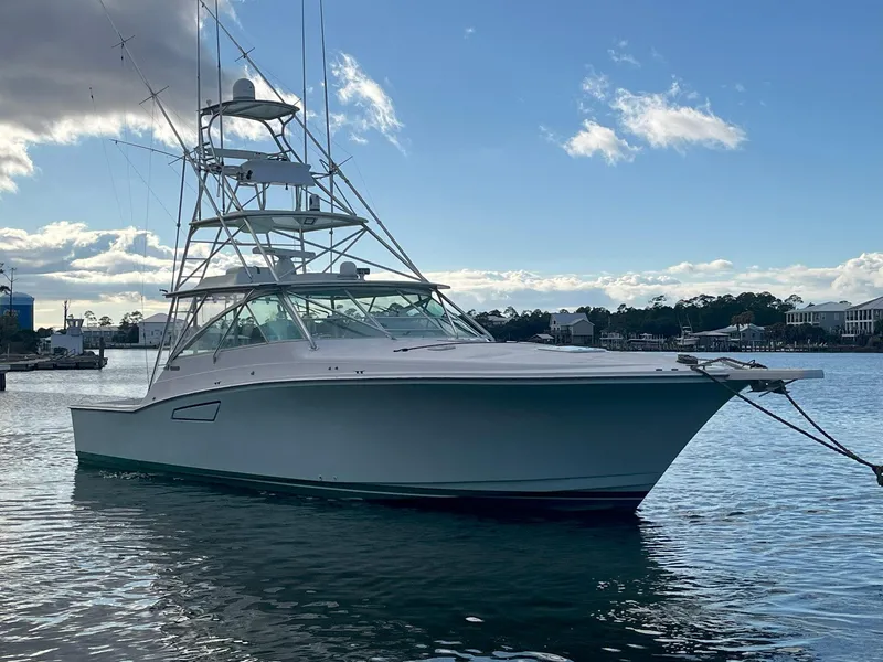 The Image of 1999 Cabo 45 Express yacht docked on calm water under a partly cloudy sky. - 1