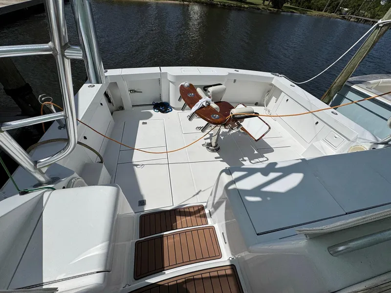 Slide: The Image of 1999 Cabo 45 Express boat deck with fishing chair, docked by the water. - 10