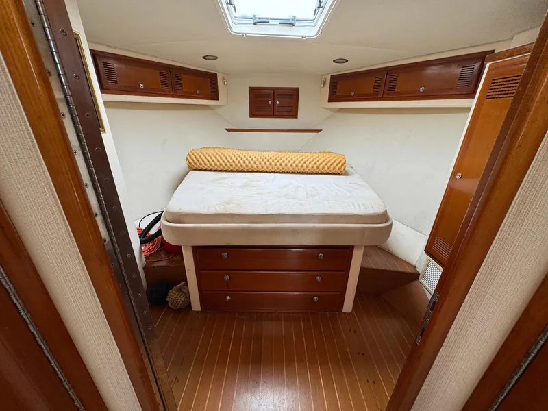 Slide: The Image of 1999 Cabo 45 Express cabin interior with bed, wooden cabinets, and overhead hatch. - 9