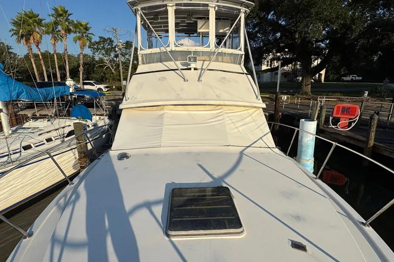 Slide: The Image of 1979 Bertram 38 Convertible boat docked, featuring a spacious deck and flybridge. - 14