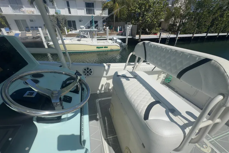 Slide: The Image of 2000 Pursuit 2870 Center Console boat interior with steering wheel and seating, docked by water. - 14