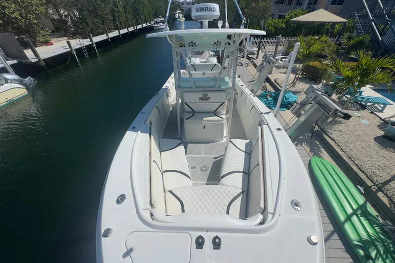 Slide: The Image of 2000 Pursuit 2870 Center Console boat docked by a canal, featuring spacious seating. - 29