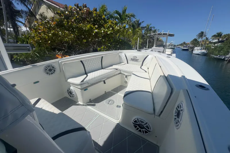 Slide: The Image of 2000 Pursuit 2870 Center Console boat with cushioned seating, docked near a canal. - 35