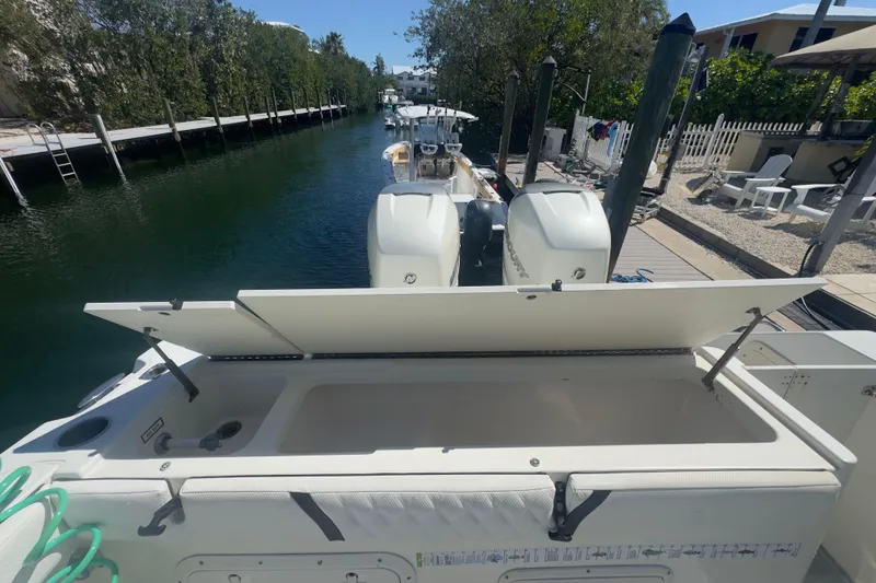 Slide: The Image of 2000 Pursuit 2870 Center Console boat with open storage compartment, docked by a canal. - 49
