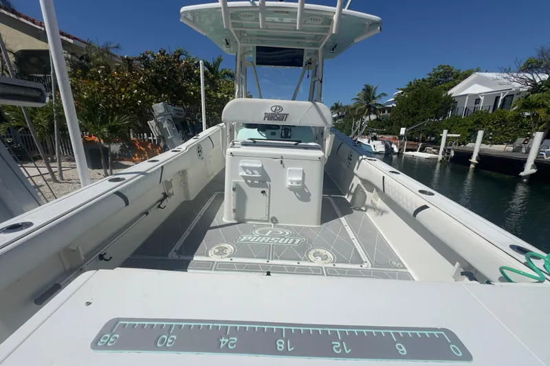 Slide: The Image of 2000 Pursuit 2870 Center Console boat docked, showcasing spacious deck and fishing features. - 50