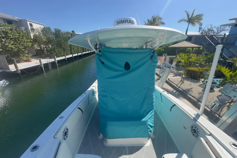 Slide: The Image of 2000 Pursuit 2870 Center Console boat docked by a canal, featuring a blue cover. - 52
