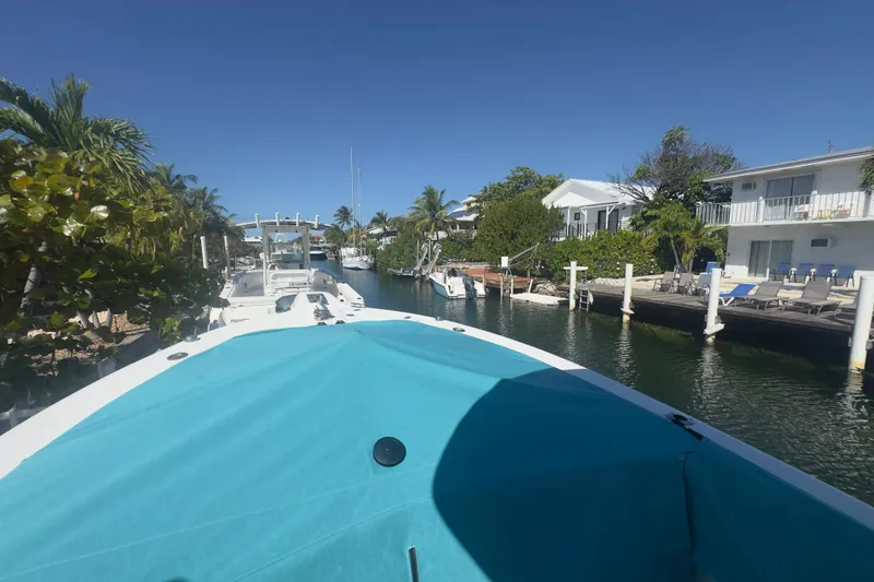 Slide: The Image of 2000 Pursuit 2870 Center Console boat docked in a scenic canal with palm trees. - 53