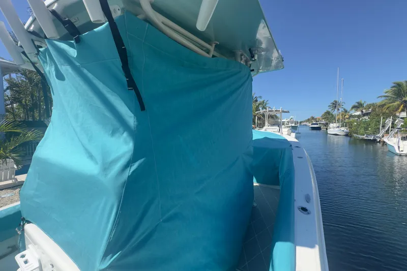 Slide: The Image of 2000 Pursuit 2870 Center Console boat with blue cover docked by a canal. - 55