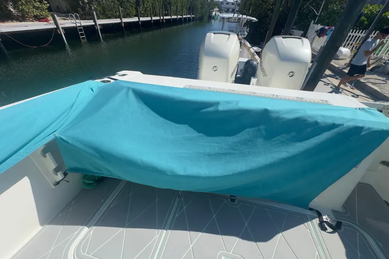Slide: The Image of 2000 Pursuit 2870 Center Console boat with turquoise cover, docked by a canal. - 56