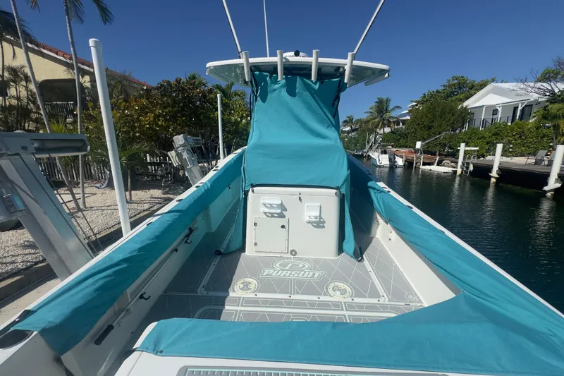 Slide: The Image of 2000 Pursuit 2870 Center Console boat docked, featuring teal covers and a spacious deck. - 57
