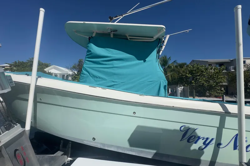 Slide: The Image of 2000 Pursuit 2870 Center Console boat with teal cover, docked under clear blue sky. - 60