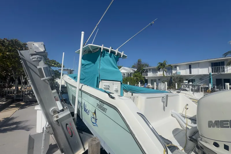 Slide: The Image of 2000 Pursuit 2870 Center Console boat docked, featuring teal cover and outboard motor. - 61
