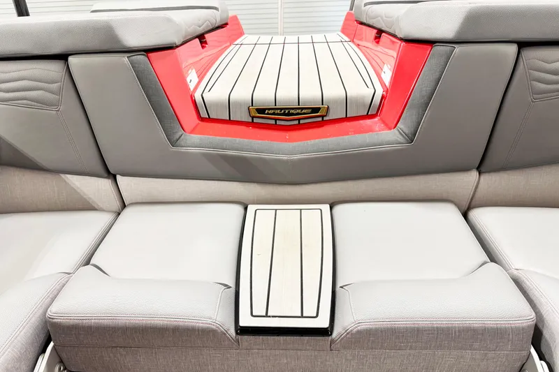 Slide: The Image of 2025 Nautique Super Air Nautique G23 Coastal Edition interior seating, gray upholstery, red accents. - 14