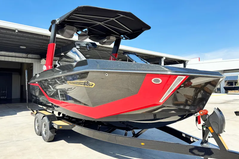 Slide: The Image of 2025 Nautique Super Air Nautique G23 Coastal Edition boat on trailer, black and red design. - 3