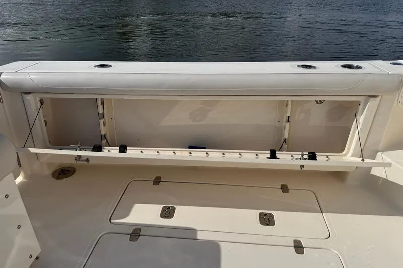 Slide: The Image of 2011 Pursuit OS 375 Offshore boat with open storage compartment by the water. - 12