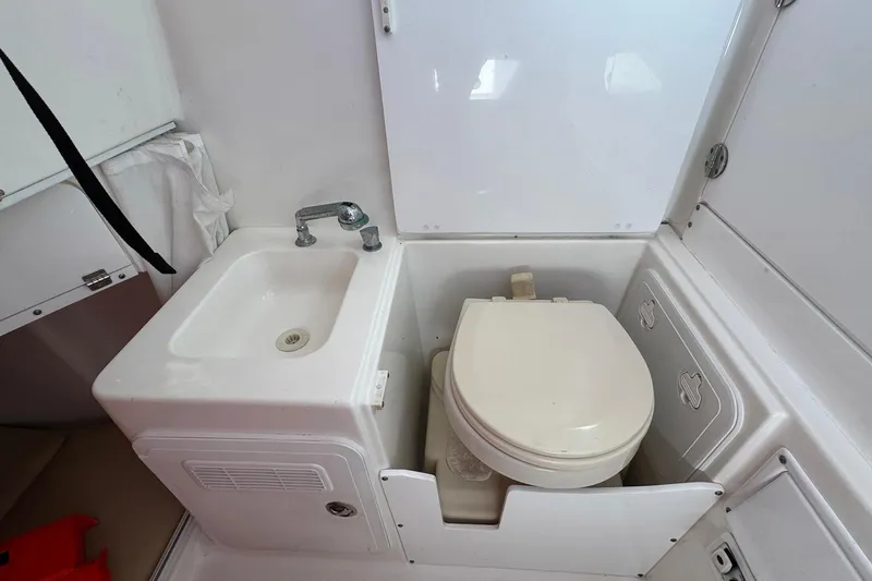 Slide: The Image of Compact bathroom in 2008 Everglades 350 Center Console boat, featuring sink and toilet. - 23