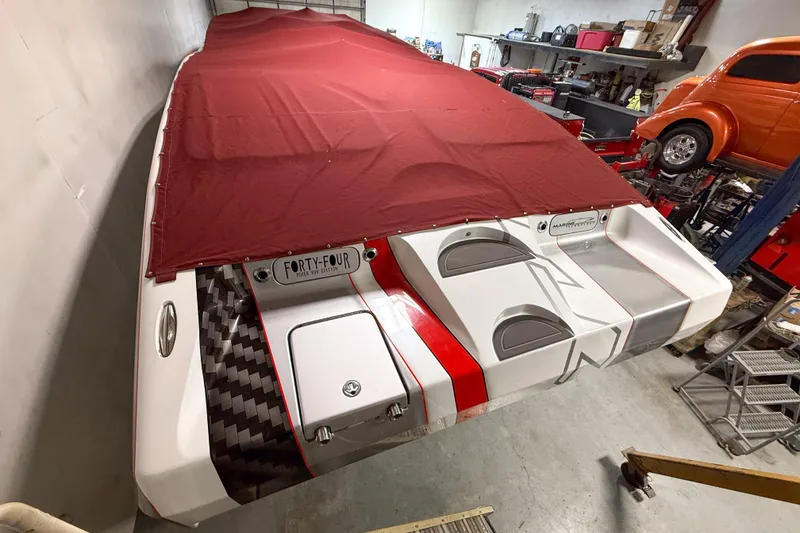 Slide: The Image of 2004 MTI 44 Pleasure Cat boat with red cover in a garage setting. - 3