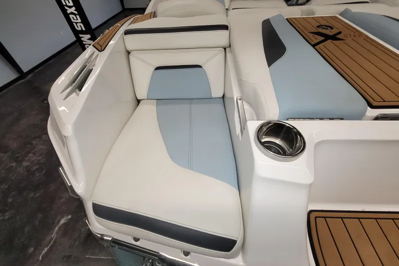 Slide: The Image of 2022 MasterCraft XStar S boat interior with white and blue seating, cup holder, and teak accents. - 14