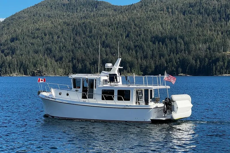 Slide: The Image of 2020 American Tug 362 cruising on a scenic lake with forested hills in the background. - 1