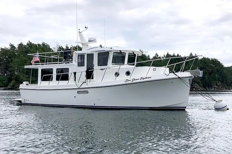 Slide: The Image of 2020 American Tug 362 boat anchored on calm water with forested background. - 4