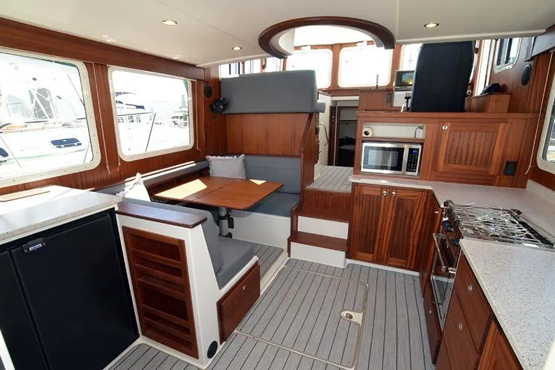 Slide: The Image of Interior of 2020 American Tug 362, featuring kitchen, dining area, and wooden cabinetry. - 9
