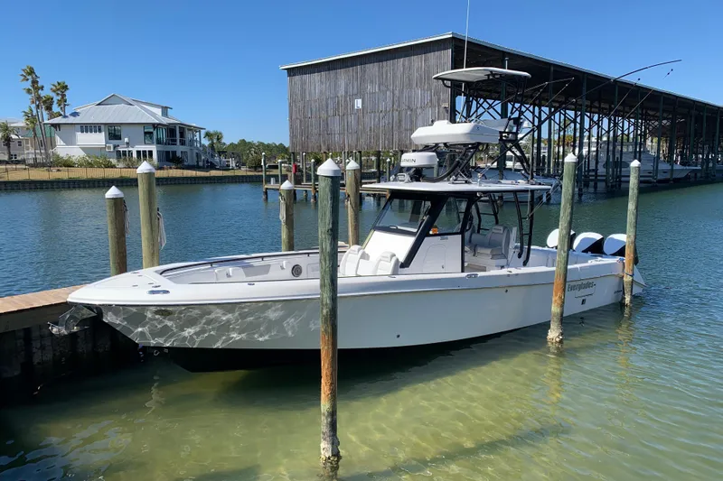 The Image of 2018 Everglades 355 Center Console boat docked in a marina with clear blue water. - 1