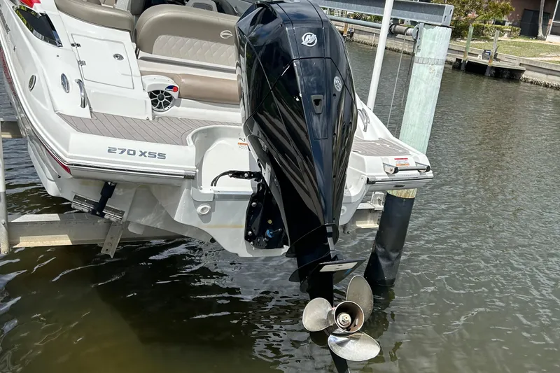Slide: The Image of Red 2022 Crownline 270 XSS boat on lift, docked by waterfront. - 13