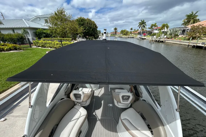 Slide: The Image of 2022 Crownline 270 XSS boat interior with modern seating and steering, docked by a canal. - 22