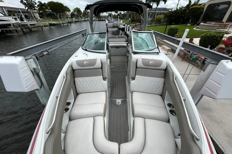 Slide: The Image of 2022 Crownline 270 XSS boat docked, featuring spacious seating and sleek design under a cloudy sky. - 36