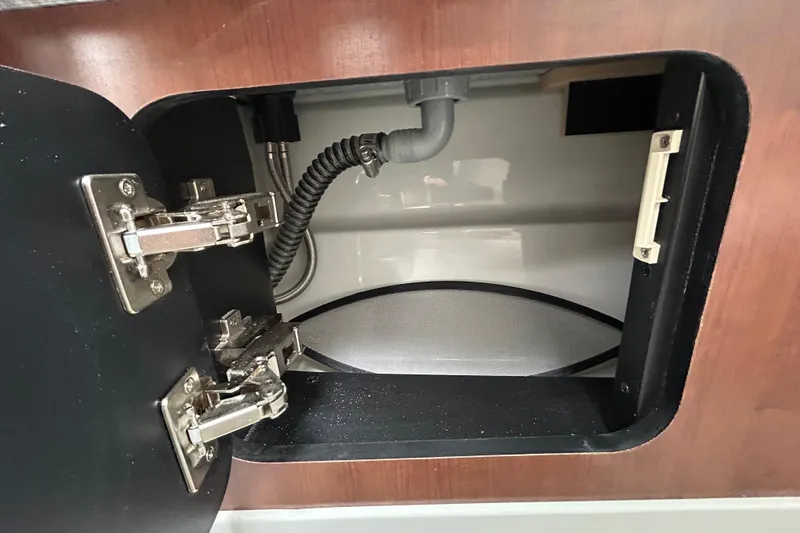 Slide: The Image of Open storage compartment in 2022 Crownline 270 XSS boat, featuring wood finish and secure latch. - 78