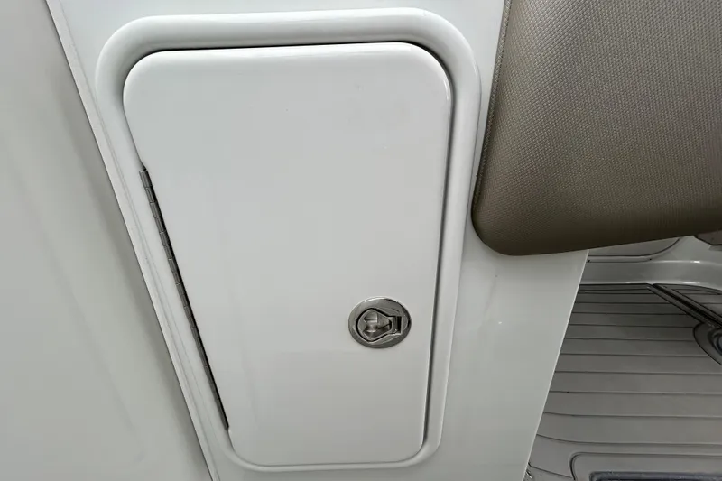 Slide: The Image of Open cabinet with plumbing inside a 2022 Crownline 270 XSS boat. - 79