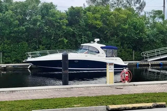 The Image of 2005 Sea Ray 390 Sundancer yacht docked near lush greenery. - 0